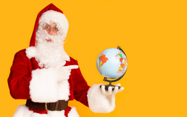Santa Claus holding globe and showing with finger on it