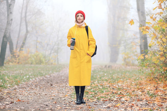 Girl Wearing Red Beanie And Yellow Raincoat Walking In The Forest