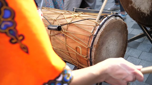 Street musician plays on an african drum djembe with drumsticks on the street