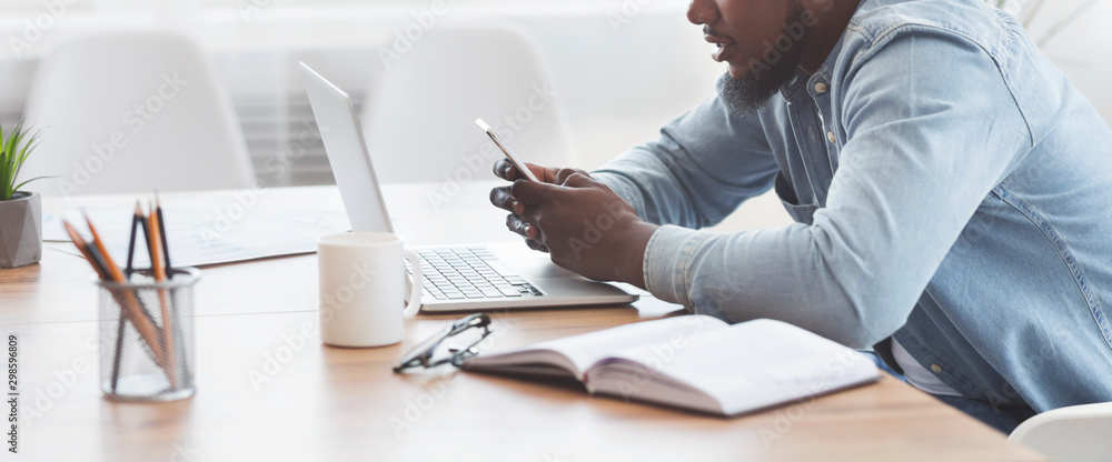 Poster african worker reading message on smartphone during work in office