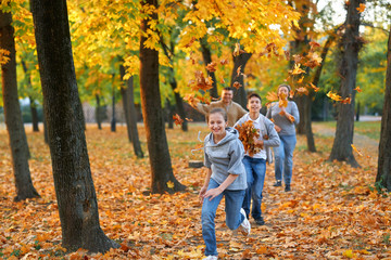 Happy family having holiday in autumn city park. Children and parents running, smiling, playing and...