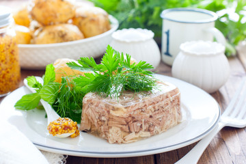 Homemade Aspic of turkey meat on a white plate with boiled potatoes, horizontal