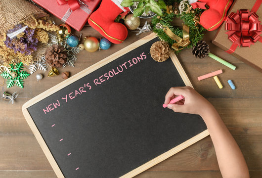 Kid Writing New Year Resolution On Black Board