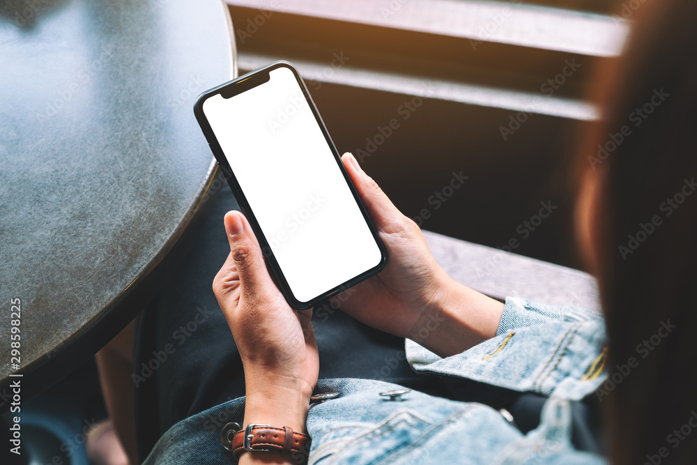 Wall mural mockup image of a woman holding black mobile phone with blank desktop screen