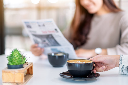 Closeup image of people reading newspaper and drinking coffee together in the morning