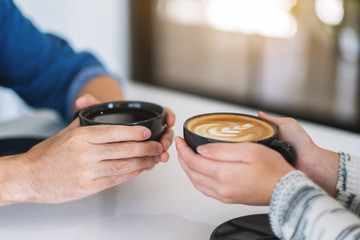 Closeup image of a man and a woman holding two coffee cups together