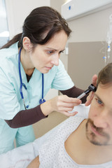 Fototapeta premium doctor inserting hearing aid in mans ear