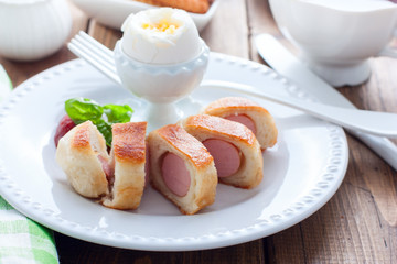 Breakfast with sausages in yeast dough on a wooden table, horizontal