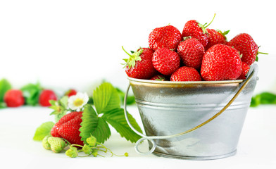 Juicy ripe tasty strawberries in  metal bucket on white wooden table.