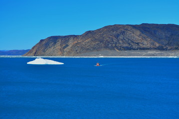 boat in the bay of the Eqip Sermia with icebergs  - melting Eqi Glacier in Greenland Disko Bay,  World of greenland travel - global warming and climate change. Summer, July