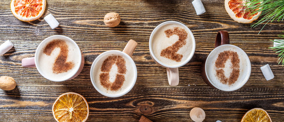 Card with numbers 2020 for New year and Christmas. Cup of coffee with figures on wooden background. Top view. Flat lay