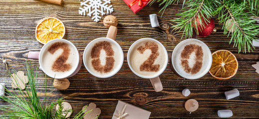 Card with numbers 2020 for New year and Christmas. Cup of coffee with figures on wooden background. Top view. Flat lay