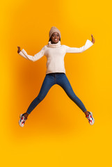 Emotional afro girl in winter hat jumping up
