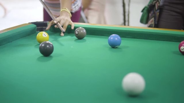 Amazing close up of people playing billiard, snooker and hitting the white ball in the green one.