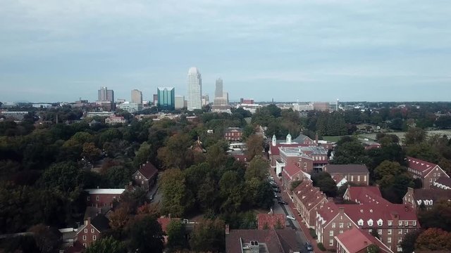 Aerial Push Old Salem in Foreground with Winston Salem NC Skyline in Background