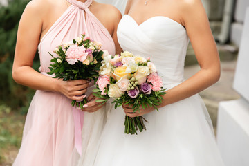Obraz na płótnie Canvas Wedding, marriage concept. Bride and bridesmaid in pink dress holding wedding bouquets