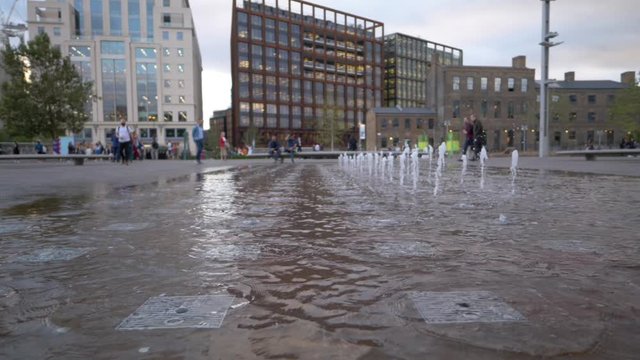 Slow motion: Water fountain in the city square. A peaceful evening in Granary Square in London, UK 1080 HD