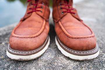 Water drops on red leather work boots close-up. The concept of water-repellent impregnation for...