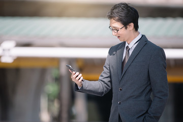 Asian Young attractive business man using taplet with big window at front building.