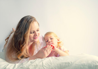 Mother and daughter lying on bed in pajamas and talking about something.Family time