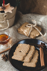 speculoos Christmas cookies on a black plate with star anise, honey and cinnamon, the effect of the film and tinting, soft focus and bokeh