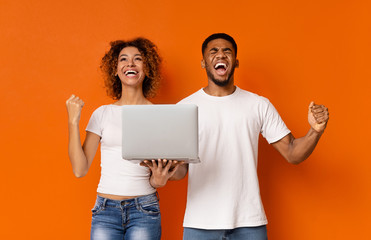 Emotional african couple with laptop enjoying win