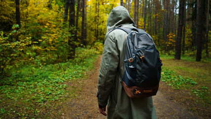 A man with backpack walks in the amazing autumn forest. Hiking alone along autumn forest paths....