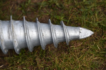 Fototapeta premium The gray colored tip of a new earth drill on a green meadow.