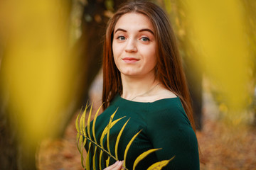 Autumn girl portraits. Emerald dress. Yellow leaves and trees. Park. Warm atmosphere.