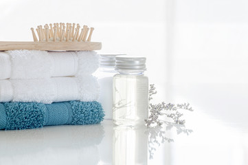 Spa set with stack of clean towels, oil bottle, wooden comb and flower on white background. Copy...