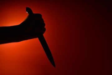 silhouette of woman holding knife on black background