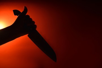 silhouette of woman holding knife on black background