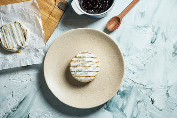 Two grilled Camembert cheese head on plate and on cutting board. light texture background. Top view...