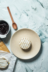 Two grilled Camembert cheese head on plate and on cutting board. light texture background. Top view with copy space. Tasty food for breakfast.