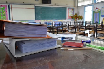many documents and stationery on the teacher's desk in the classroom after school without students