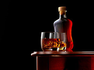 Two glasses of double whiskey and ice on a wooden table. In the background, a closed bottle of whiskey. Low key.
