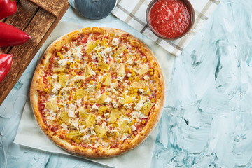 Homemade oven-baked Hawaiian pizza with chicken and pineapple, red sauce. Composition with crispy pizza, tomatoes on a light background. Copy space