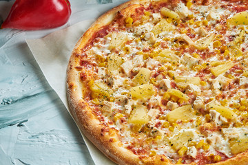 Homemade oven-baked Hawaiian pizza with chicken and pineapple, red sauce. Composition with crispy pizza, tomatoes on a light background. Copy space