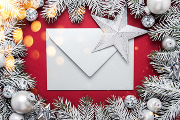 Merry Christmas and Happy Holidays greeting card, frame, banner. New Year. Noel. Silver, white and red Christmas ornaments and fir tree on red background top view. Winter holiday xmas theme. Envelope.