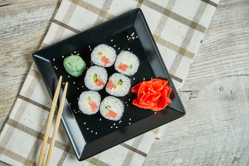 Sushi roll with salmon on a black plate on a wooden background. Japanese food. Seafood