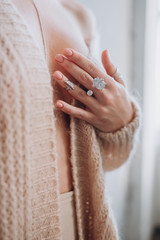a girl in a beige jacket shows rings on her hands