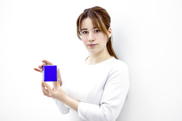 Female medical worker is demonstrating a package with cream. A woman with beauticians holds a box in her hands. Person doctor on a white wall background.