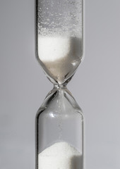 Hourglass in the foreground with falling grains of sand