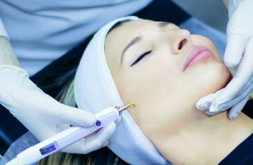 Facial massage, microcurrent therapy, anti-wrinkle. Young woman rejuvenates, radiant skin. Facial rejuvenation and facelift using radio wave therapy, modern technology