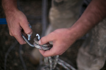 Rope access worker inspecting closing rigging on locking Karabiner gate its attached into safety 25...