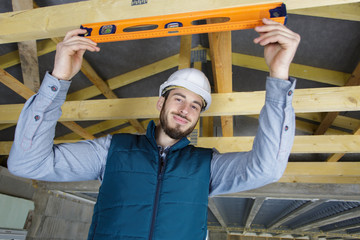 worker checks the level of wooden house structure