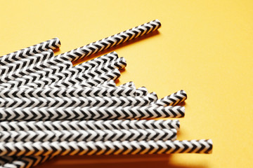 A lot of black paper straws on a yellow background. Top view. Place for text.