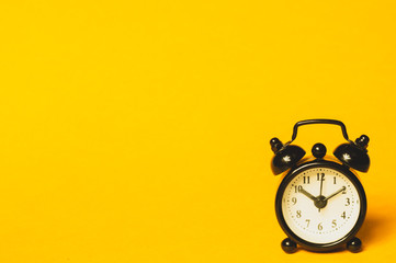 Classic alarm clock on yellow background. vintage watch with round dial