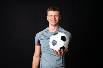 Handsome young football player man over isolated black wall