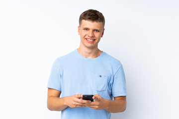Young handsome man over isolated white background sending a message with the mobile